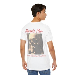 May include: White t-shirt with a skull graphic and the words "Memento Mori" in red script. Below the skull image, the text reads "Remember Death and Live Fully". The shirt is made of a soft material.