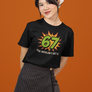 May include: Black t-shirt with the number "67" in green, set against a yellow burst design. The text "YOU WOULDN'T GET IT" is below the number. The person is wearing a white bandana and a striped skirt.