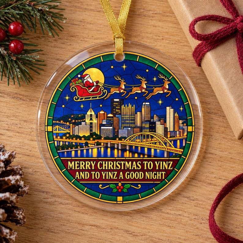May include: A round, clear acrylic Christmas ornament featuring a stained-glass style illustration of the Pittsburgh skyline at night, Santa in a sleigh with reindeer, and the text MERRY CHRISTMAS TO YINZ AND TO YINZ A GOOD NIGHT.