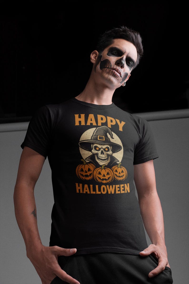May include: Black t-shirt with a Halloween-themed graphic. The design features a skull wearing a witch hat, surrounded by three carved pumpkins. The words "HAPPY HALLOWEEN" are printed above and below the central image in orange.