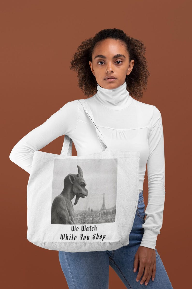 Op de afbeelding: Witte draagtas met een zwart-wit afbeelding van een waterspuwer en de Eiffeltoren. De tekst "We Watch While You Shop" staat onder de afbeelding.