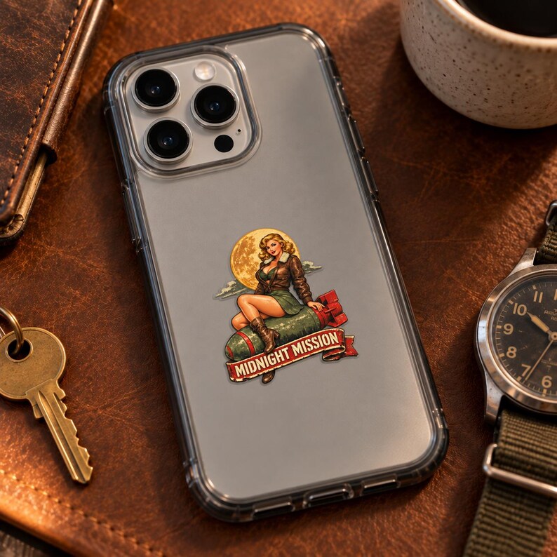 K&ouml;nnte beinhalten: Eine transparente Smartphone-H&uuml;lle mit einem Aufkleber, der eine blonde Pin-up-Figur in brauner Jacke und gr&uuml;nem Rock zeigt, die auf einer gr&uuml;nen Bombe sitzt. Hinter der Figur ist ein gelber Mond. Ein rotes Banner zeigt den Text Midnight Mission.
