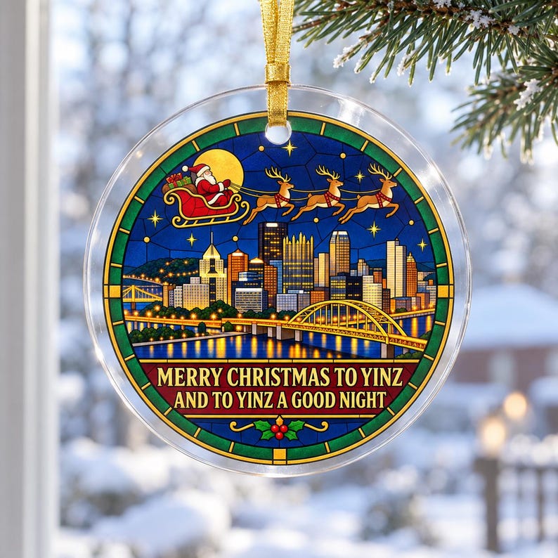 May include: A round clear acrylic Christmas ornament featuring a stained glass style illustration of the Pittsburgh skyline at night with Santa and his reindeer flying above. The text reads MERRY CHRISTMAS TO YINZ AND TO YINZ A GOOD NIGHT.