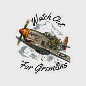 May include: A sticker featuring a vintage airplane with a cartoon gremlin riding on the wing. The plane has a red and yellow nose, a shark mouth design, and the text "Sweet Revenge." The sticker reads "Watch Out For Gremlins."