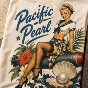 May include: An off-white t-shirt featuring a graphic of a blonde person in a sailor-style top and floral sarong sitting on a bomb. The text Pacific Pearl is printed in blue script. The design includes a large seashell with a pearl and hibiscus flowers.