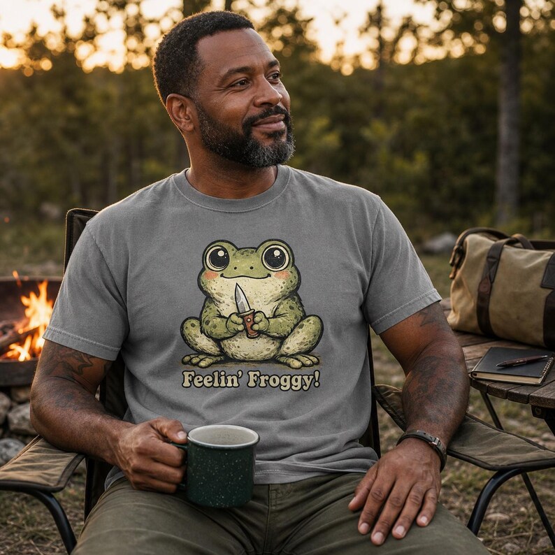 Może przedstawiać: Szary t-shirt z kr&oacute;tkim rękawem z grafiką zielonej żaby trzymającej mały n&oacute;ż. Pod żabą znajduje się napis Feelin' Froggy! ciemnobrązową czcionką. Koszulka posiada okrągły dekolt i standardowy kr&oacute;j, wykonana jest z bawełnianego materiału.