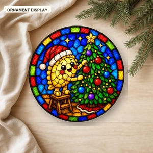Puede incluir: Un adorno circular con una ilustraci&oacute;n estilo vitral de un personaje amarillo con gorro de Pap&aacute; Noel rojo, subido a un taburete de madera para decorar un &aacute;rbol de Navidad verde con adornos rojos, morados y azules.