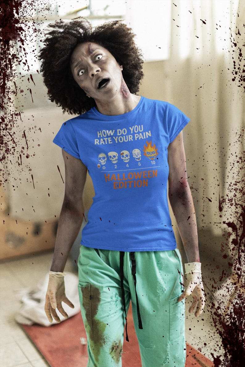 May include: A blue t-shirt with the text "HOW DO YOU RATE YOUR PAIN" and a pain scale graphic, Halloween Edition. The person is wearing green scrubs and has a zombie-like appearance.