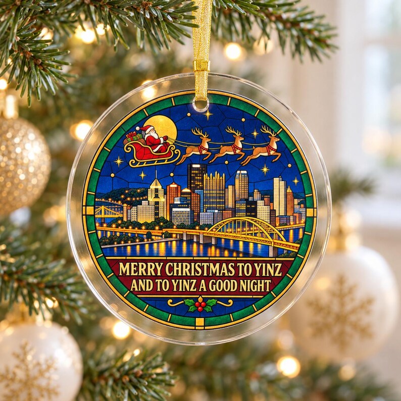 May include: A round, clear acrylic Christmas ornament featuring a stained-glass style illustration of the Pittsburgh skyline at night, with Santa and his reindeer flying above. The text reads, "MERRY CHRISTMAS TO YINZ AND TO YINZ A GOOD NIGHT."