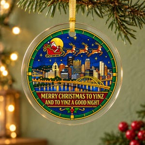 May include: A round, clear glass ornament featuring a stained-glass style illustration of the Pittsburgh skyline at night, with Santa and his reindeer in the sky. The text reads, "MERRY CHRISTMAS TO YINZ AND TO YINZ A GOOD NIGHT."