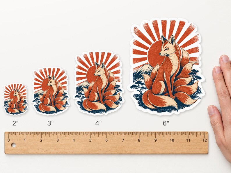 May include: Four die-cut stickers featuring a nine-tailed fox sitting before a red sun and mountain. Sizes are labeled 2, 3, 4, and 6 inches above a wooden ruler. The design includes orange, red, and dark blue tones with a white border.