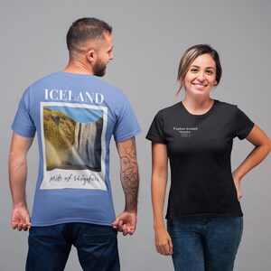 May include: Two people wearing t-shirts. One is light blue with "ICELAND" and a waterfall image. The other is black with "Explore Iceland" text. Both shirts are short-sleeved and made of a soft material.