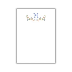 Könnte beinhalten: Weißes Briefpapier mit einem hellblauen Buchstaben "M" und floralen Verzierungen. Das Design zeigt eine zarte Anordnung von rosa und gelben Blumen mit grünen Blättern, die eine weiche, elegante Ästhetik erzeugt. Ideal für personalisierte Notizen.