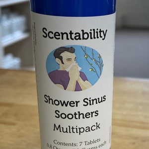 May include: A blue cylindrical container with a white lid, labeled "Scentability Shower Sinus Soothers Multipack." The label includes an illustration of a person blowing their nose. Contains 7 tablets, 0.8 ounces/23 grams each.