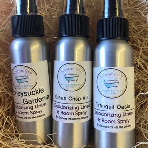 Pode incluir: Tr&ecirc;s frascos de spray prateados com tampas pretas e r&oacute;tulos brancos. Os r&oacute;tulos dizem "Honeysuckle Gardenia", "Clean Crisp Air" e "Tranquil Oasis". Cada frasco cont&eacute;m 75 ml de spray desodorizante para roupa de cama e ambiente.