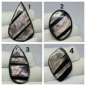 May include: Four polished cabochons labeled 1 through 4, featuring a pearlescent, iridescent shell-like material inlaid with diagonal black stripes. Each piece has a smooth, glossy finish and distinct geometric shapes including teardrop and oval.