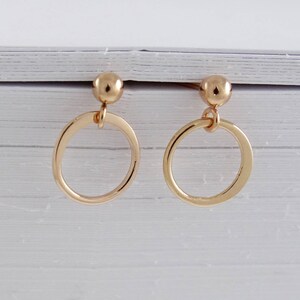 May include: A pair of gold hoop earrings with a small ball at the top of each hoop.