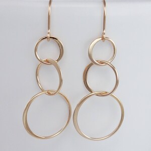 Peut inclure: Boucles d'oreilles en or avec trois cercles entrelac&eacute;s. Les cercles sont de tailles diff&eacute;rentes et sont reli&eacute;s &agrave; un crochet.