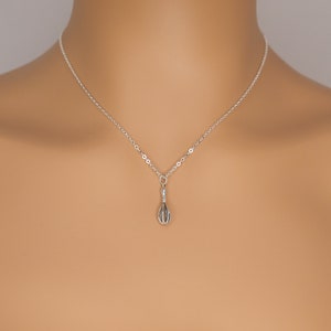 Puede incluir: Un collar de cadena de plata con un peque&ntilde;o colgante de batidor de plata.