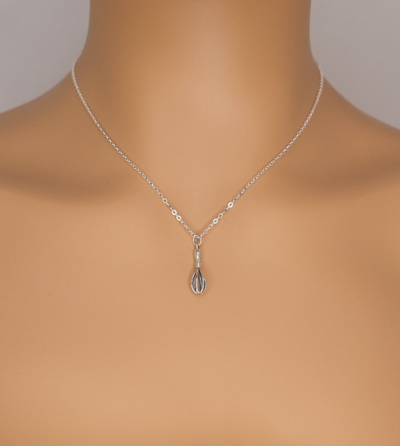 Puede incluir: Un collar de cadena de plata con un peque&ntilde;o colgante de batidor de plata.