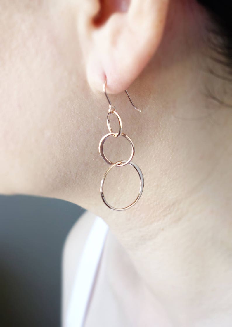 Peut inclure: Boucles d'oreilles pendantes en or rose avec trois cercles interconnect&eacute;s.