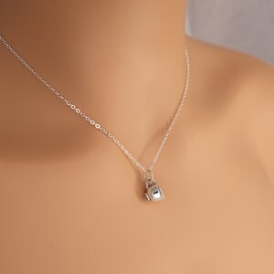 May include: A silver chain necklace with a small silver teacup pendant.