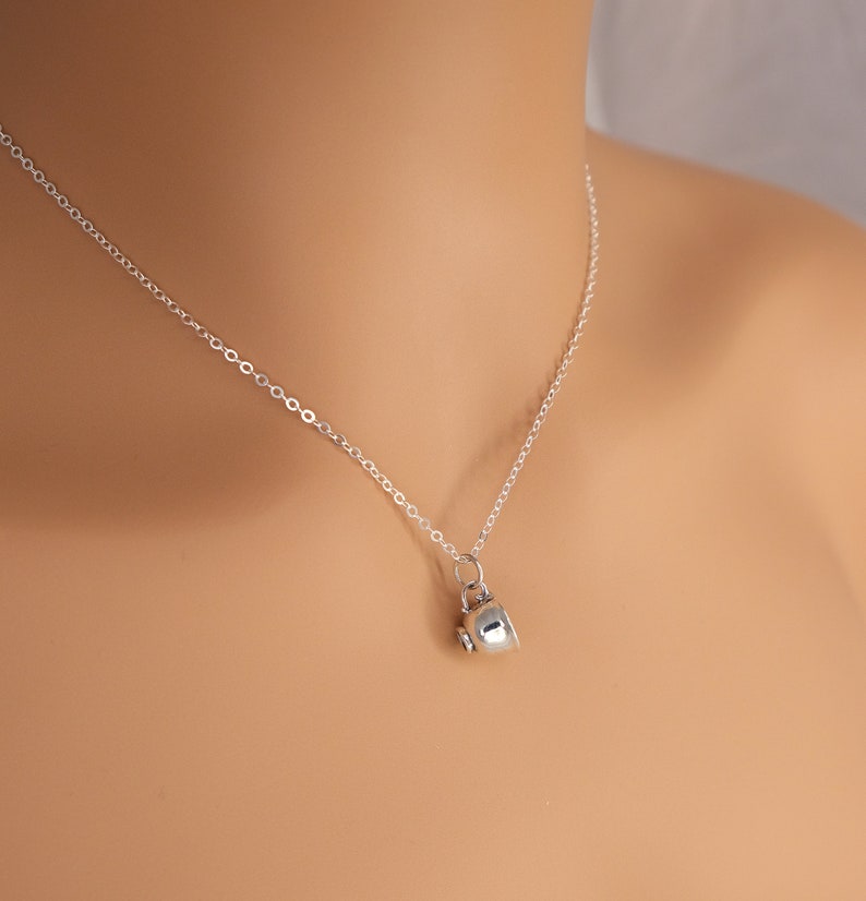 May include: A silver chain necklace with a small silver teacup pendant.