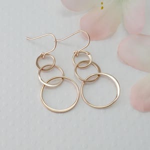 Peut inclure: Boucles d'oreilles pendantes en or rose avec quatre cercles interconnect&eacute;s de tailles diff&eacute;rentes.