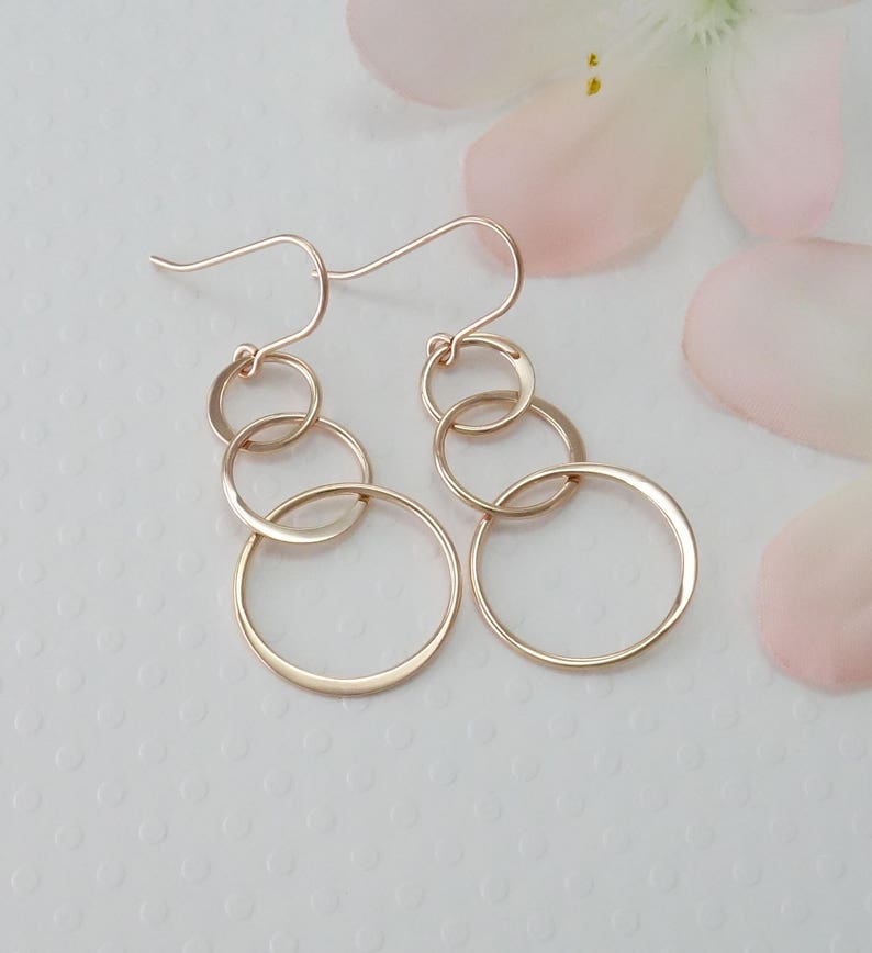 Peut inclure: Boucles d'oreilles pendantes en or rose avec quatre cercles interconnect&eacute;s de tailles diff&eacute;rentes.