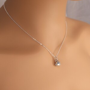 May include: A silver chain necklace with a small silver teapot charm.