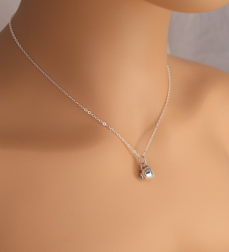 May include: A silver chain necklace with a small silver teapot charm.