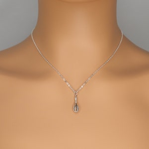 Puede incluir: Un collar de cadena de plata con un peque&ntilde;o dije de batidor de alambre.