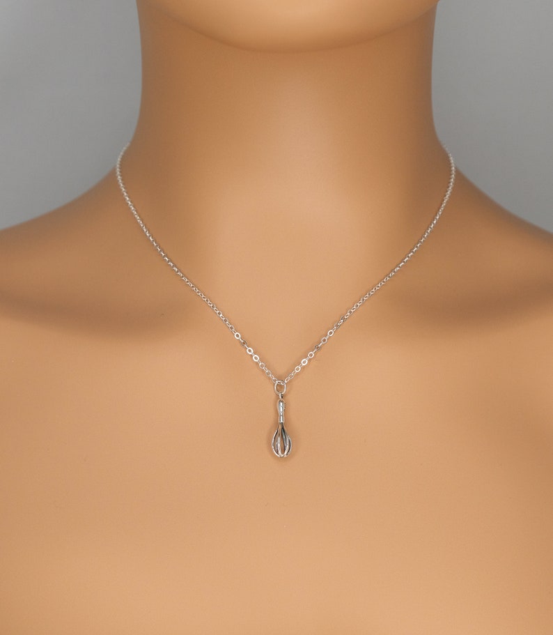 Puede incluir: Un collar de cadena de plata con un peque&ntilde;o dije de batidor de alambre.