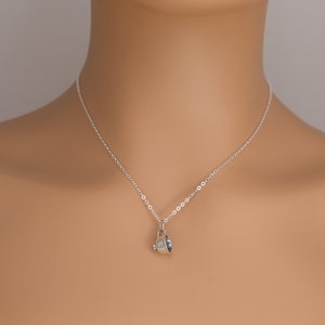 May include: A silver chain necklace with a small silver teacup pendant.