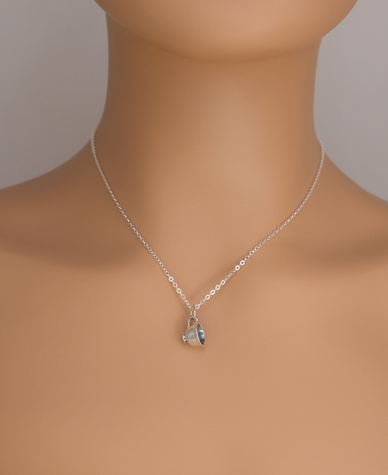 May include: A silver chain necklace with a small silver teacup pendant.