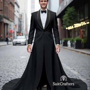 May include: A formal black tuxedo with a long coat and a black bow tie. The tuxedo has a satin lapel and a long, flowing skirt. The image is set on a city street.