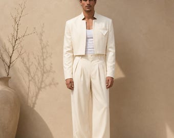 May include: A cream-colored cropped blazer with a mandarin collar and a single chest pocket, worn over a white tank top with matching high-waisted, wide-leg pleated trousers. The SuitCrafters logo is visible in the top right corner.