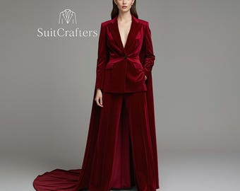 May include: A deep red velvet suit with a blazer, wide-leg pants, and a cape. The blazer has a single button closure and pockets. The suit is from SuitCrafters.