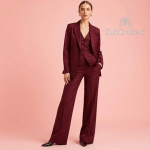 May include: A deep burgundy three-piece suit consisting of a tailored blazer, a button-up vest, and wide-leg trousers. The ensemble features a structured lapel and clean lines. The logo SuitCrafters is visible in the upper right corner of the image.
