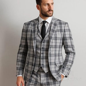 May include: A three-piece suit in a gray and black plaid pattern. The suit includes a jacket, vest, and trousers. The jacket has a two-button closure and the vest has a button-down front. The suit is paired with a white dress shirt and a black tie.