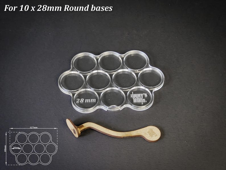 Op de afbeelding: Transparante acryl basis houder voor 10 ronde bases, elk met een diameter van 28 mm, met de tekst "28 mm" en "Jimmy's Mills". Een houten handvat is ook inbegrepen. De tekst "For 10 x 28mm Round bases" staat bovenaan.