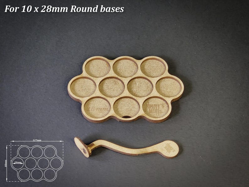 May include: A light brown wooden tray with ten circular recesses, each for 28mm round bases, and a matching handle. The tray has the text "For 10 x 28mm Round bases" at the top. The tray is 127mm x 65mm.