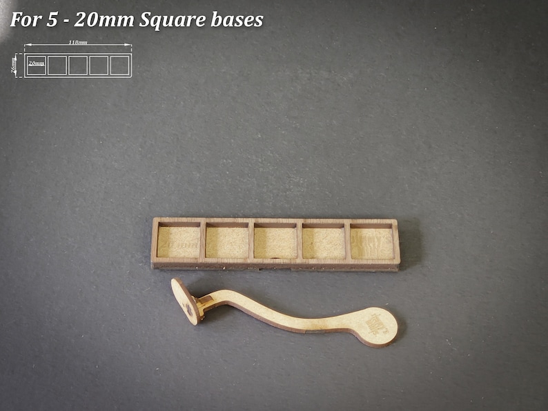 Puede incluir: Soporte de base cuadrada de madera con cinco compartimentos y una herramienta de madera curvada. El texto "For 5 - 20mm Square bases" est&aacute; en la parte superior. El soporte mide aproximadamente 11,1 cm de largo.