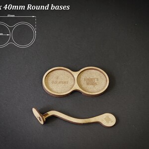 May include: Wooden round bases for miniatures, with a handle. The bases are designed for 40mm miniatures. The image also includes a diagram with measurements in millimeters. The text on the base says "Jimmy's Minis".