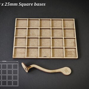 Puede incluir: Organizador de bases cuadradas de madera para miniaturas, con 25 compartimentos, cada uno de 2,5 cm cuadrados, y un asa curva. El texto "For 20 x 25mm Square bases" est&aacute; en la parte superior. Un diagrama muestra las dimensiones.