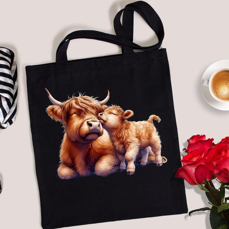 Puede incluir: Bolso tote negro con una ilustraci&oacute;n detallada de una vaca de las Tierras Altas y su ternero. La vaca est&aacute; tumbada y el ternero la est&aacute; abrazando. La obra de arte es en tonos marrones y beige, con asas negras.