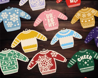 Könnte beinhalten: Eine Sammlung von zehn Weihnachtspullover-Ornamenten in verschiedenen Farben, darunter Rot, Grün, Blau und Rosa. Jedes Ornament hat ein einzigartiges Design, wie Schneeflocken, Lichter und das Wort "CHEER".