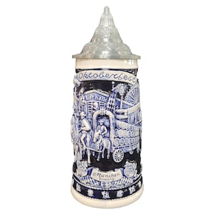 May include: A ceramic Oktoberfest beer stein with a detailed blue and white relief design. The stein features a metal lid and is decorated with scenes of a fair, the words "Oktoberfest" and "Munchen Germany".