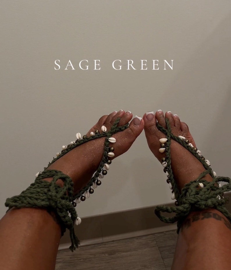 Puede incluir: Sandalias descalzas de ganchillo verde salvia adornadas con conchas blancas y peque&ntilde;as cuentas de bronce. Las sandalias se envuelven alrededor del tobillo y los dedos de los pies, con el texto "SAGE GREEN" en el fondo.