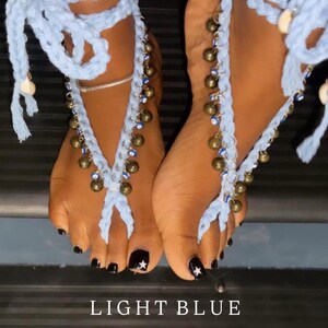 Puede incluir: Joyer&iacute;a de pie de ganchillo azul claro con cascabeles dorados colgantes y cuentas azules. La joyer&iacute;a se envuelve alrededor del pie y el tobillo. El texto "LIGHT BLUE" y "**LIMITED EDITION**" est&aacute; en la parte inferior de la imagen.